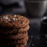 a stack of double cholate chip cookies on a black wire cooling rack