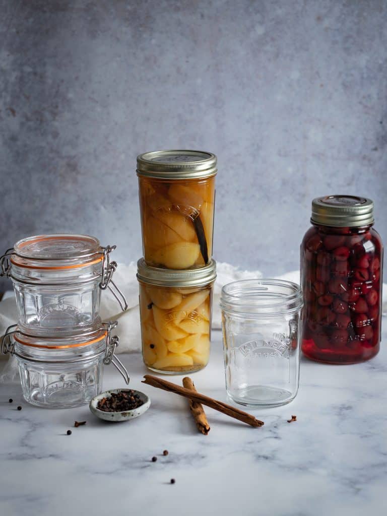 Six Kilner preserving jars. Two are filled with pears in a vanilla sugar syrup. One is filled with preserved cherries. TThe remaining jars are empty. Image by Emma Lee - The Irishman's Wife