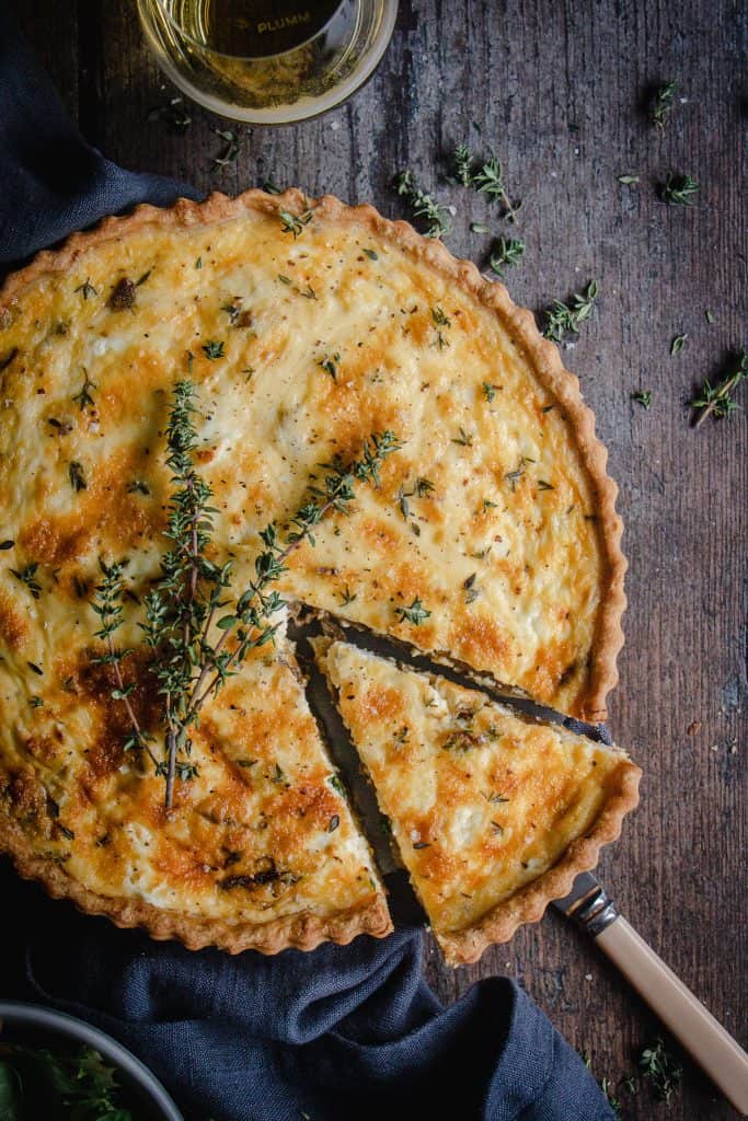 caramelized onion and goats cheese tart with a slice cut ready to serve