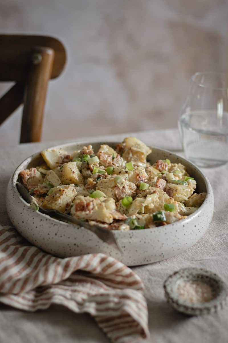 A grey speckled bowl sits on a table with a spoon in it ready to serve.