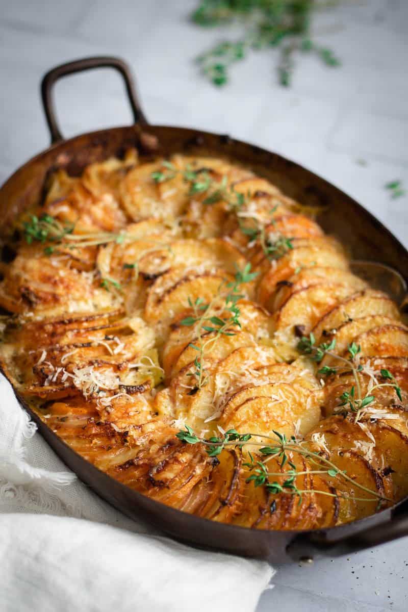 an copper oval roasting pan of black garlic potato gratin
