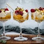 three cocktail glasses of eton mess on a timber board