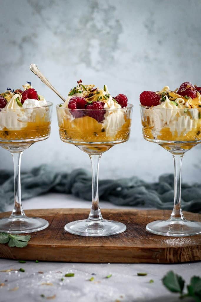 three cocktail glasses of Eton Mess for dessert on a timber board