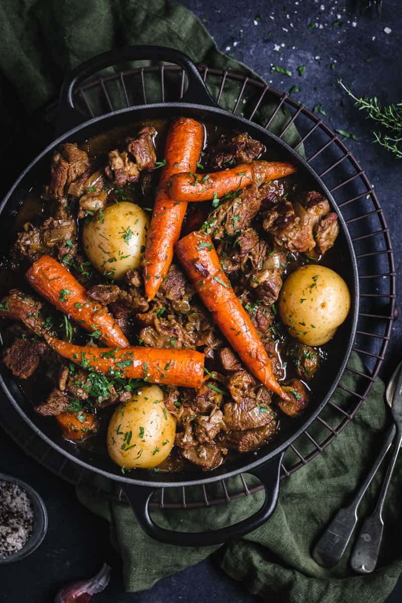 A black cast iron pot of slow cooked, Irish lamb Stew on a bench