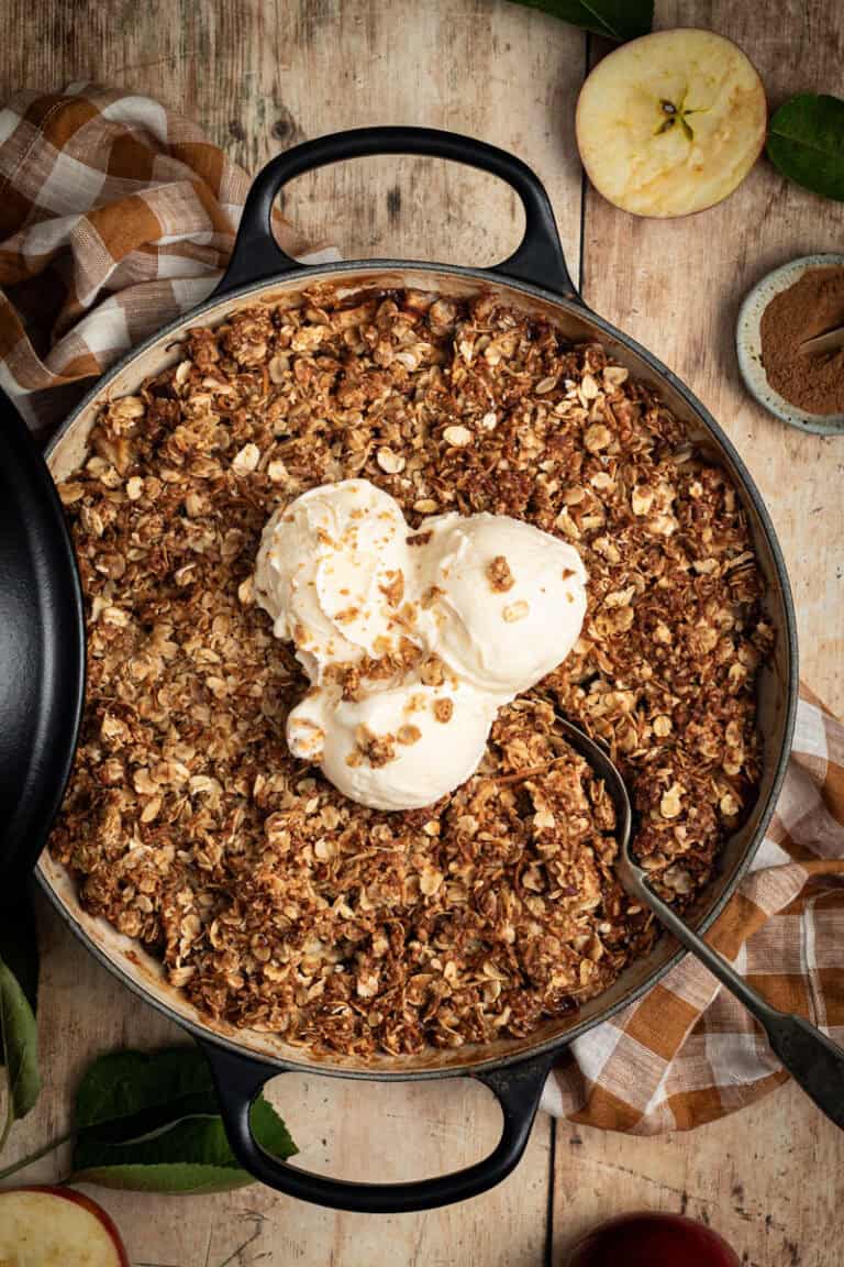 An apple and walnut crumble in a double handled shallow braiser.
