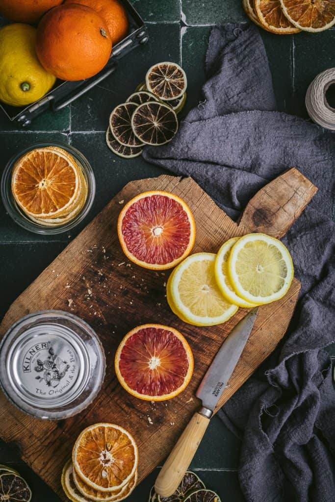 flatlay of different citrus fruits in different stages getting prepared for dehydrating