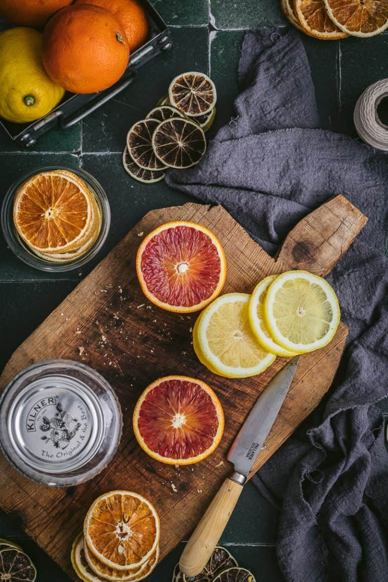 flatlay of citrus fruits being cut up on a timber board to dehydrate. Also some already dehydrated stacks of limes and lemons in the images