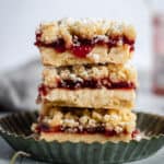 a stack of strawberry jam crumble bars sitting in a tart pan