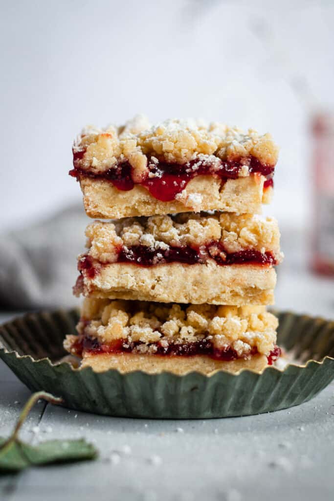 a stack of strawberry jam crumble bars sitting in a tart pan