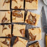 flatlay of a tray of baked biscoff cheesecake slice cut into squares with a bite taken out of one piece