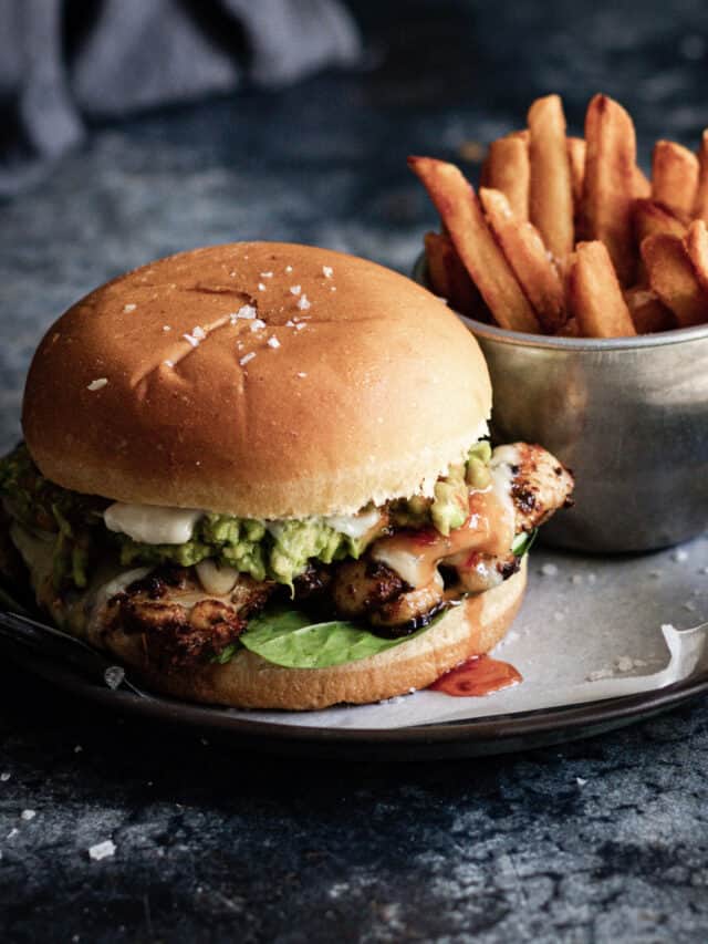 Close up of a cajun chicken burger with sweet chili sauce dripping down the side