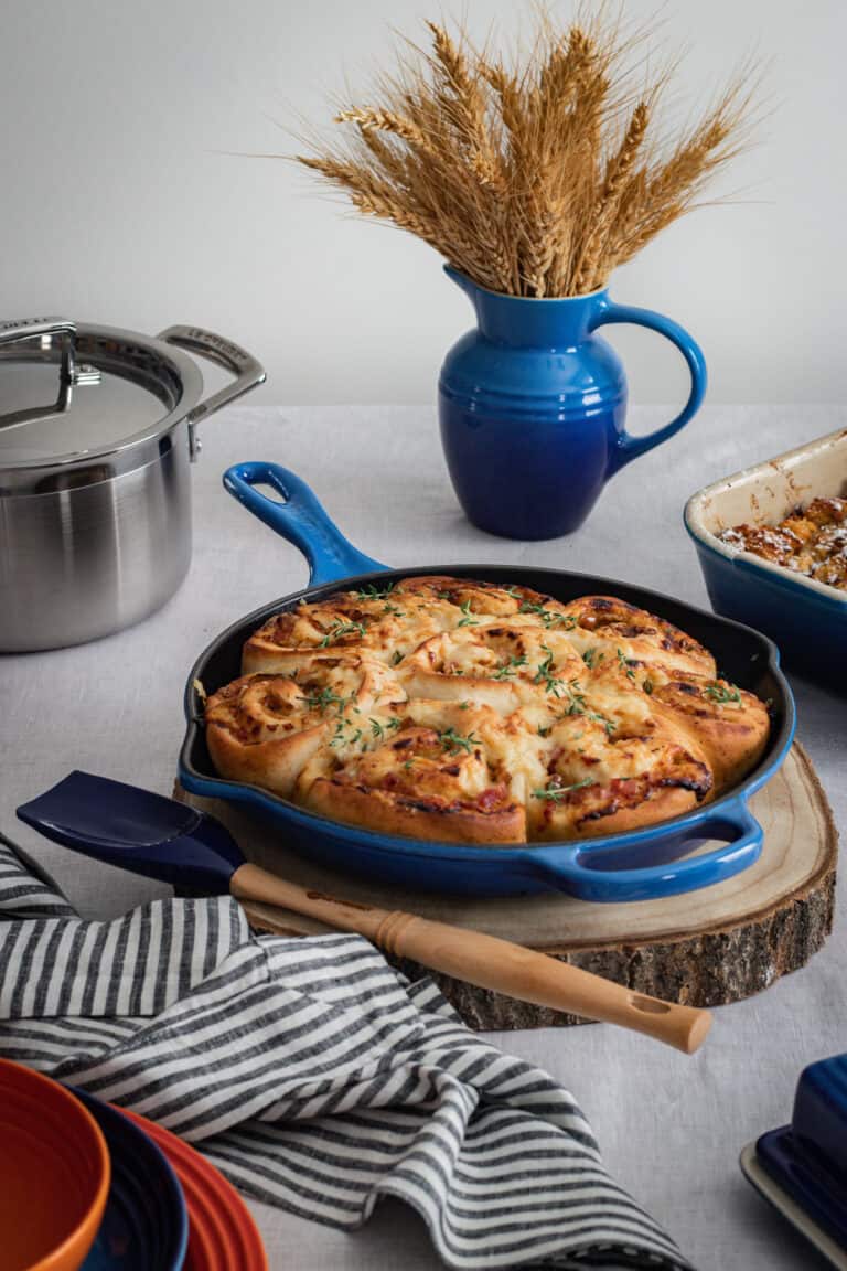A blue cast iron skillet of savoury ham cheese and caramelized onion scrolls.
