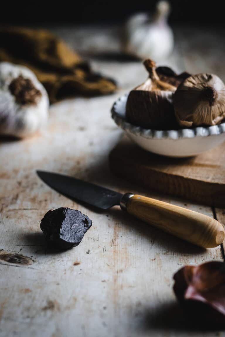A black garlic clove cut to reveal it's black interior.