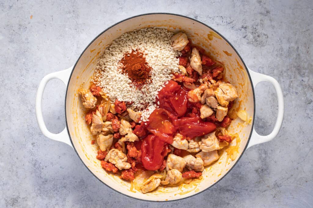 rice, paprika, canned tomatoes and saffron are added to the risotto pan.