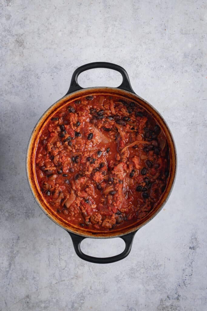 A slow cooked pot of Dutch oven chili con carne is cooked and ready to serve.