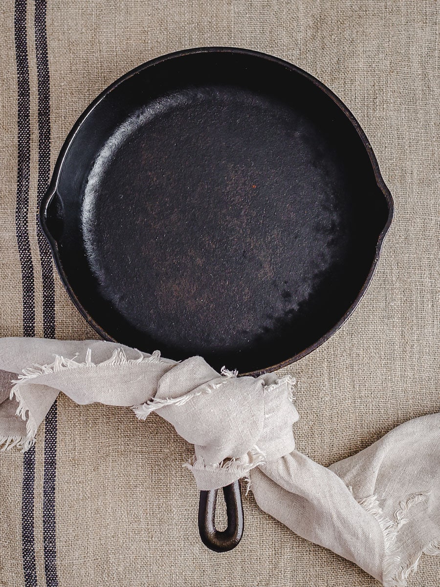 A well-seasoned cast iron skillet on a linen tea towel.