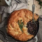 The cooked beef bourguignon pie with a serving spooned out of it.