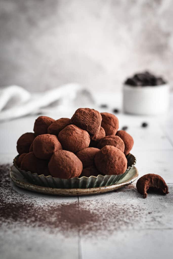 A tart tin full of homemade Bailey's Truffles. A single truffle is off to one side with a bite eaten from it.
