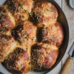 A white cast iron pan with bacon and cheese rolls baked in it.