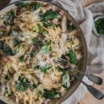 A white cast iron shallow casserole of fettuccine boscaiola finished with shallots, English spinach and parmesan.
