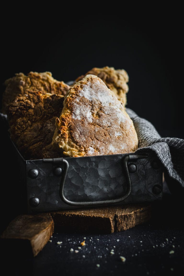 A metal tin full of golden soda bread farls.