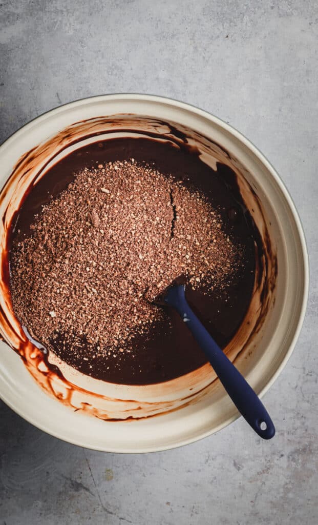Hazelnut crumb is added to the  melted chocolate bowl.