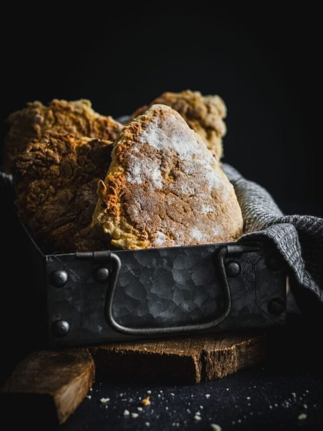 A metal tin full of golden soda bread farls.