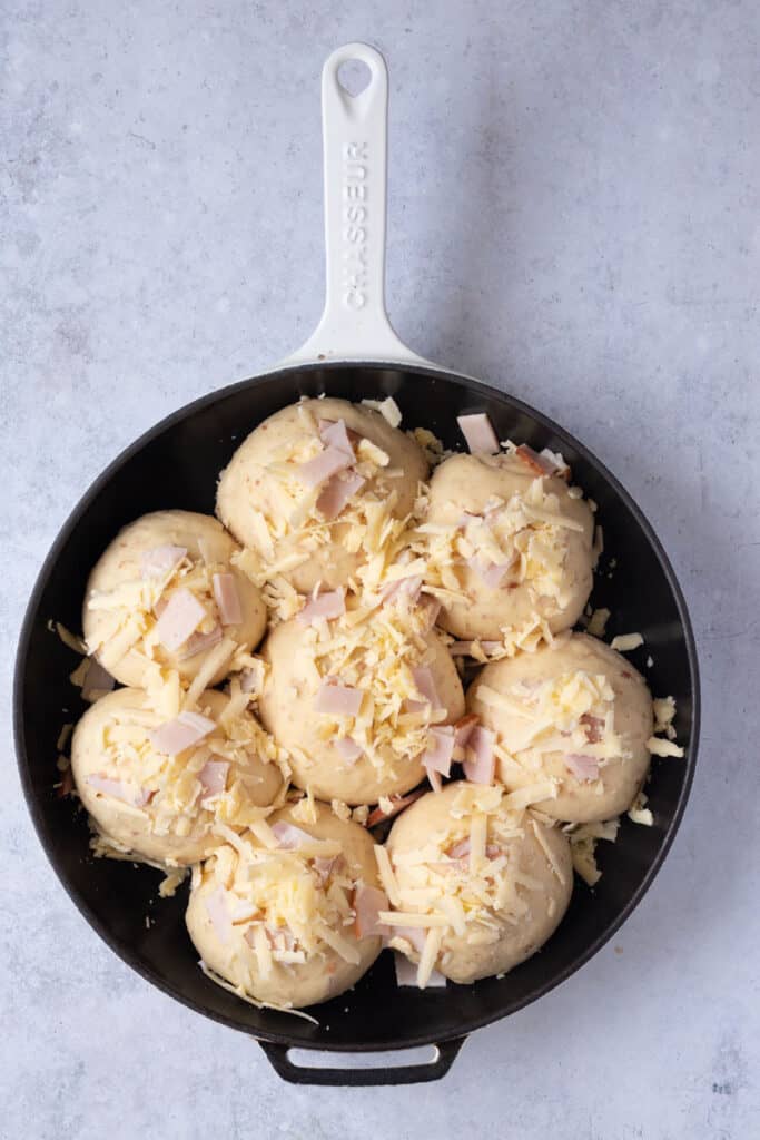 Buns glazed and topped with bacon and cheese ready to go into the oven.