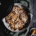 A black cast iron Dutch oven with a loaf of soda bread in it and a pot of honey beside.