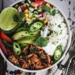 A chipotle chicken salad and rice bowl is on a vintage cream and green tray. A pot of salt and cutlery sit beside.
