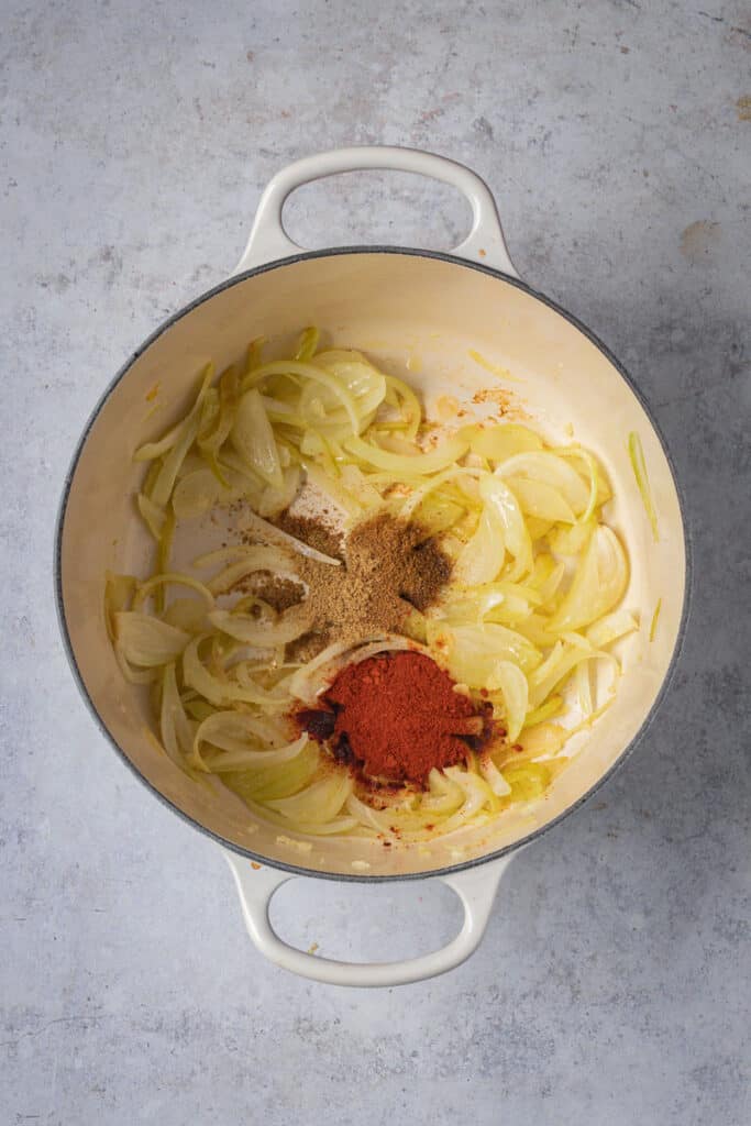 Onions, garlic and spices sauteed in olive oil in a cream colored Dutch oven.