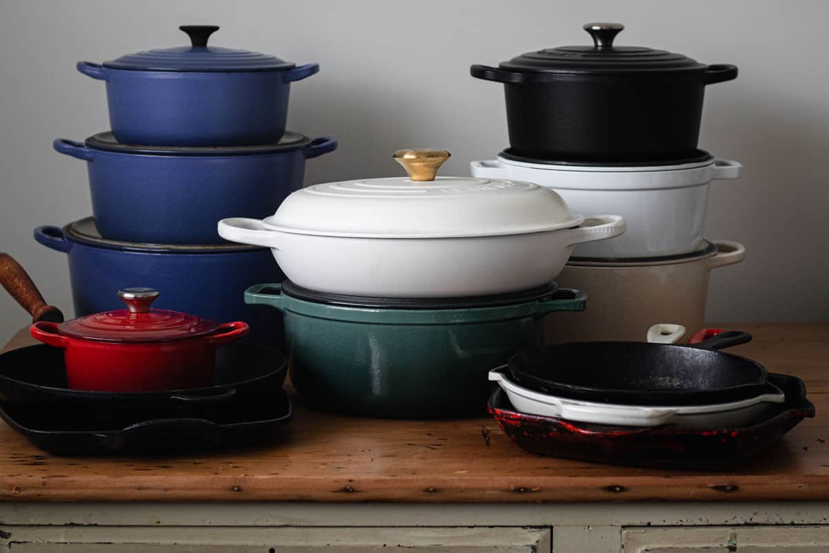 A collection of different cast iron cookware pieces stacked on a table.