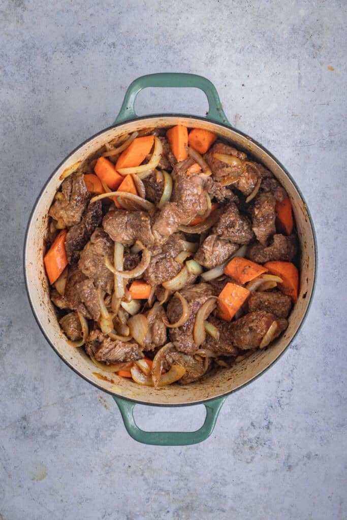 Root vegetables, saute onion and garlic and browned meat are combined in the pot.