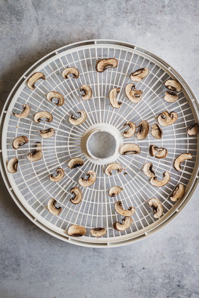 Dehydrated mushrooms slices in a round dehydrator rack.
