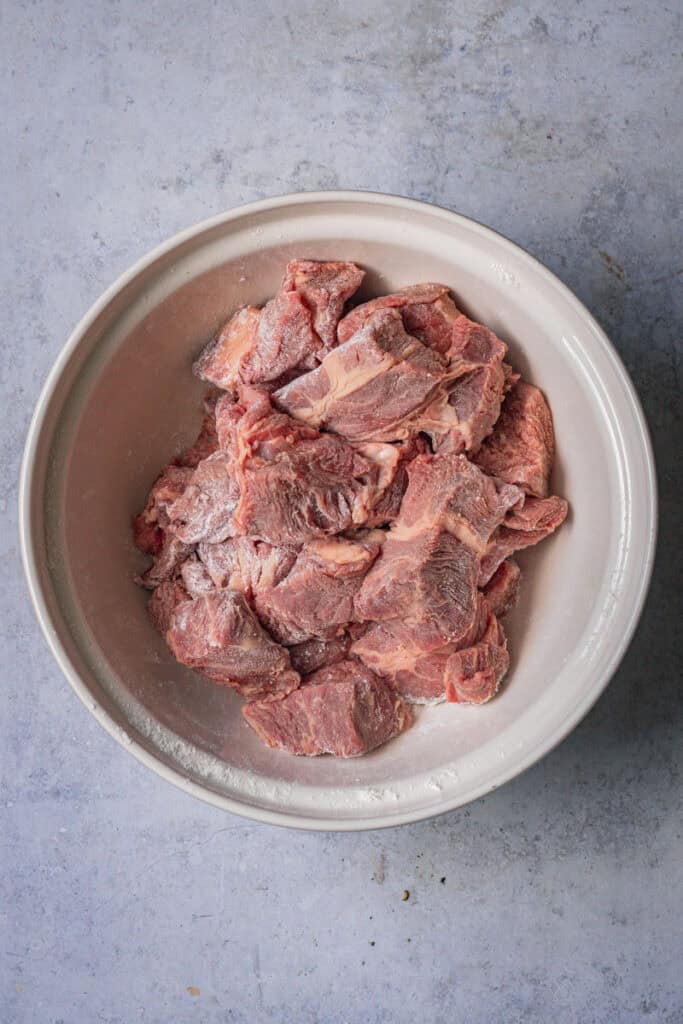 A bowl of beef chunks coated in flour.