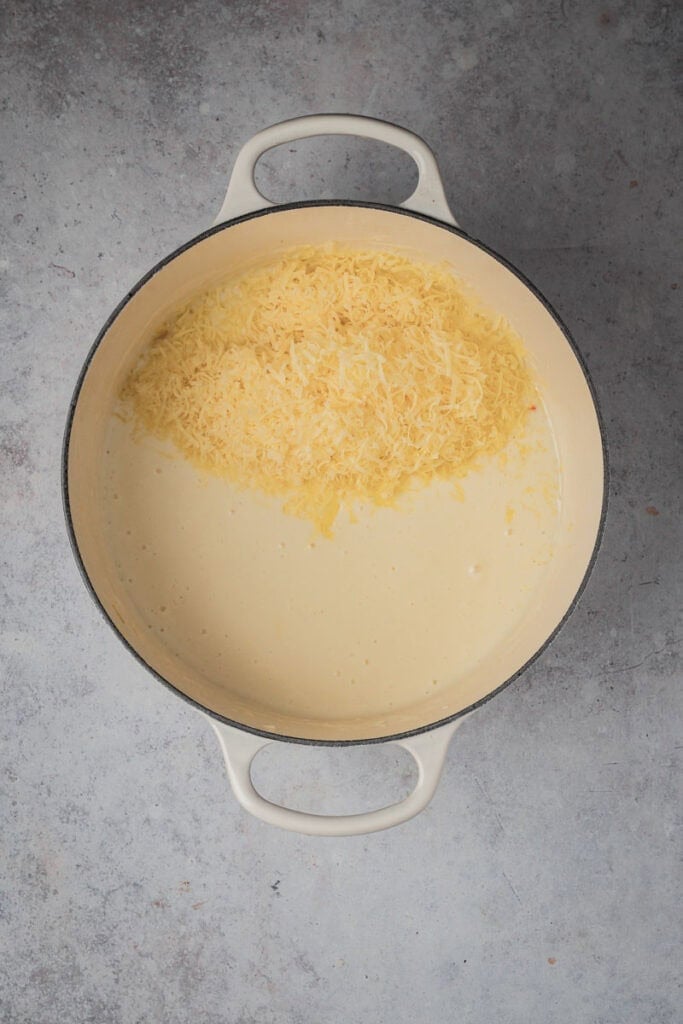 Grated cheese melting into the white sauce.