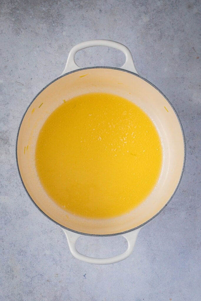 Butter melted in a cream colored enamel cast iron casserole.