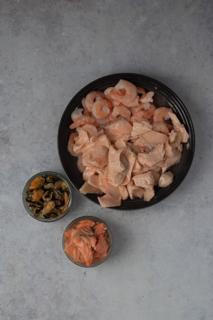 Poached and canned seafood sitting in three bowls.