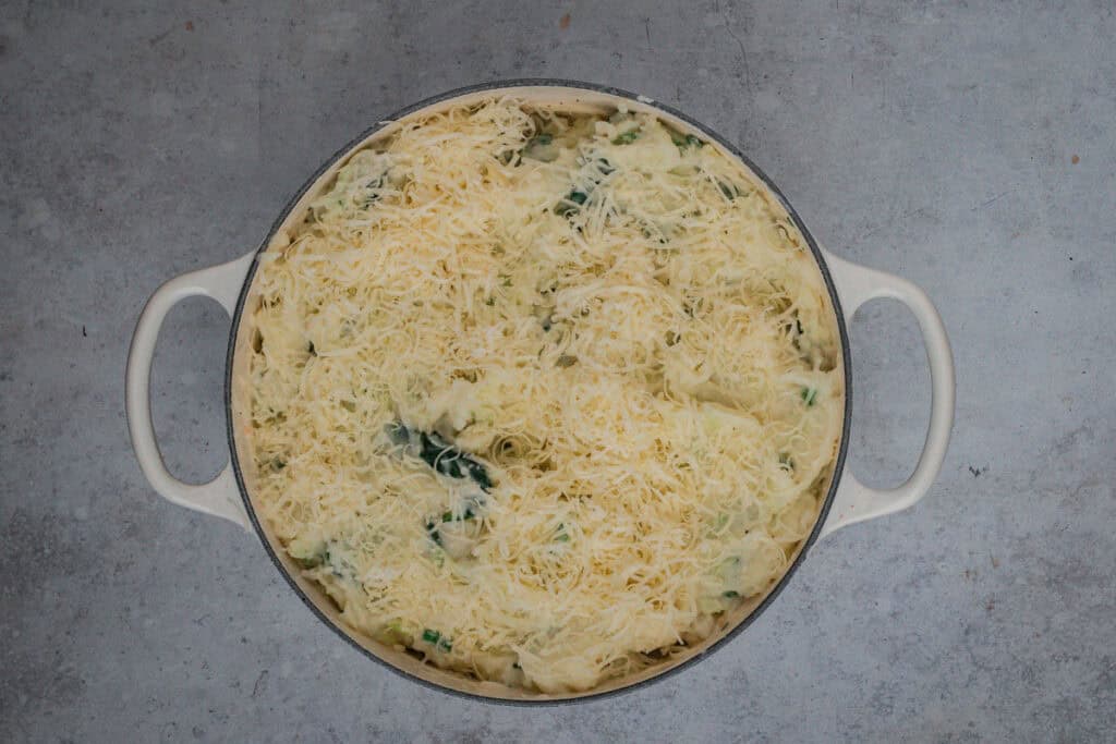 The finished seafood pie topped with colcannon and cheese ready to be baked in the oven.