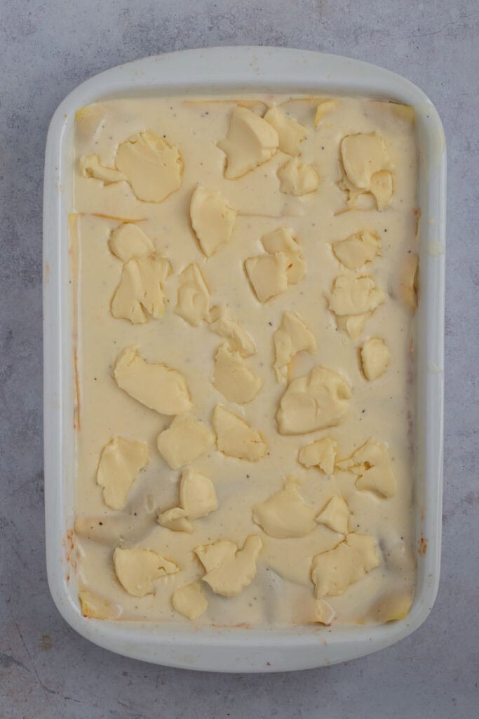 The lasagna before it goes into the oven. The top bechamel layer has been dotted with sliced mozzarella cheese.