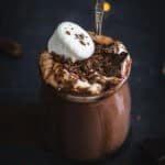 A glass jar of Baileys hot chocolate topped with whipped cream, marshmallows and chocolate shavings.