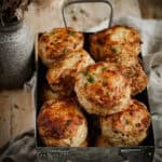 A metal tray of cheese and bacon scones. A small bunch a dried flowers sit beside.