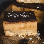 A close up of a piece of caramel slice on a timber board.