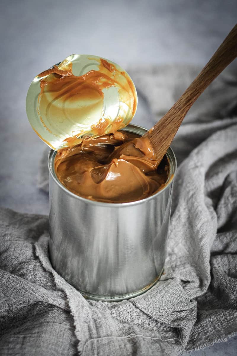 A silver can of dulce de leche with the lid peeled back revealing the creamy caramel.
