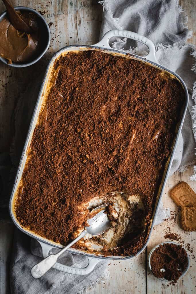 A cast iron roasting pan of speculoos tiramisu. A bite has been taken out of one end with a spoon.