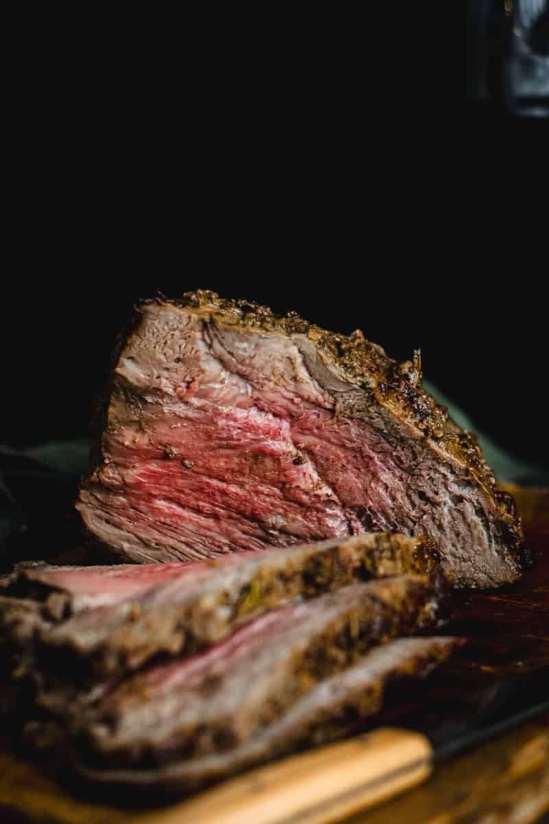 A medium rare topside beef roast on a wooden cutting board.