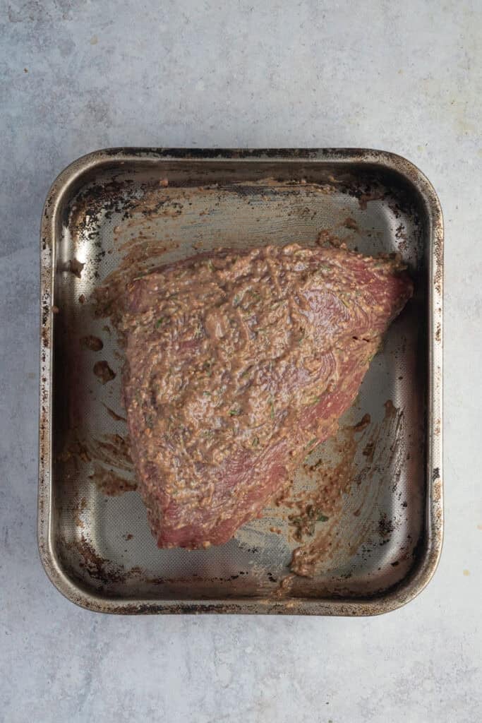 A piece of beef topside marinating on a roasting tray.