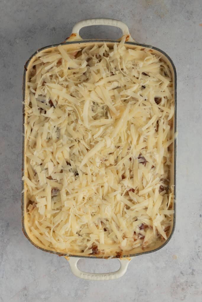 Cheese has been grated and spread all over the top of the potato bake before it is baked again.