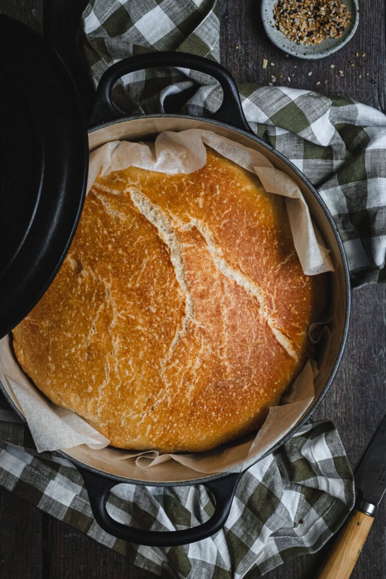 A black Dutch oven with a loaf of homemade bread in it.