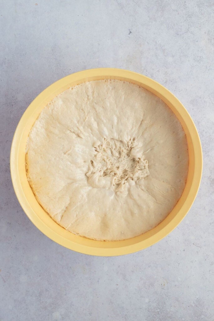 A large bowl with proved dough that has rested overnight in the fridge.
